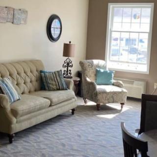 A cozy living room with a sofa, armchair, and large window allowing natural light.