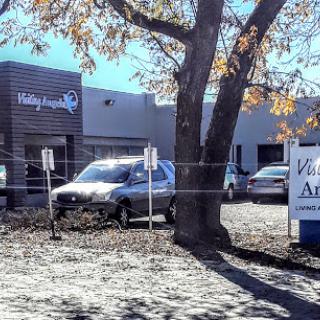 A view of a commercial building with a parked vehicle and signage in front.