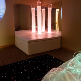 A serene therapeutic space featuring illuminated columns and a cozy seating area, designed for relaxation and sensory experiences.