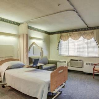 A hospital patient room with a bed, chair, and window.
