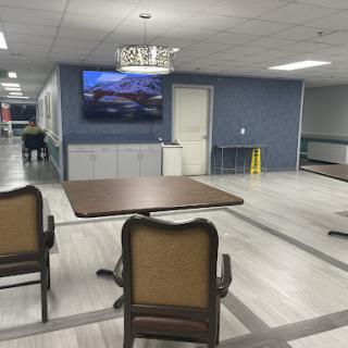 A spacious indoor area featuring a table, chairs, and a television on the wall.