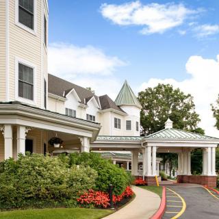 A large, attractive residential building with a landscaped entrance and covered porch.