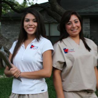 Two women in uniform smiling outdoors.