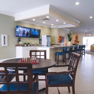 A modern living and dining area featuring a television, table with chairs, and bar stools.