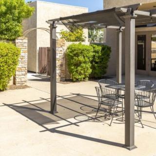 A sunny outdoor patio featuring a modern pergola and metal seating area.