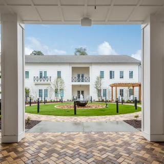 A view of a white building through an open entrance, overlooking a landscaped courtyard.
