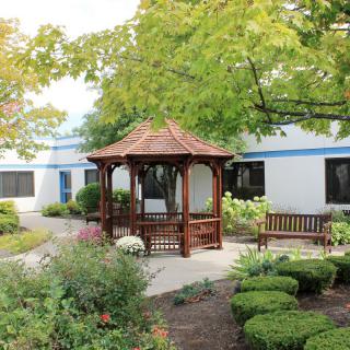 A peaceful garden setting with a wooden gazebo and lush greenery.