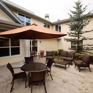 A cozy backyard patio with a table, chairs, and an umbrella.