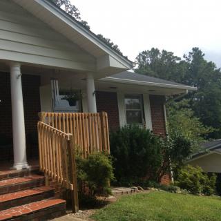 A brick house with a porch featuring columns and a small front yard.