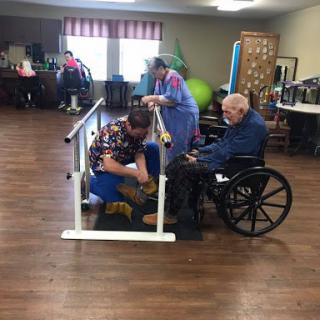 A scene from a rehabilitation facility where seniors engage in physical therapy exercises with assistance.