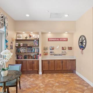 A cozy reading nook with a bookshelf, table, and decorative wall clock.