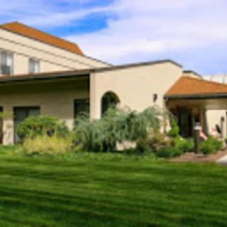 A view of a residential house with a well-maintained lawn and garden under a blue sky.