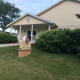 A small building with a covered entrance and neatly trimmed landscaping.