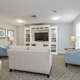 A cozy living room with comfortable sofas, armchairs, and a TV surrounded by bookshelves.
