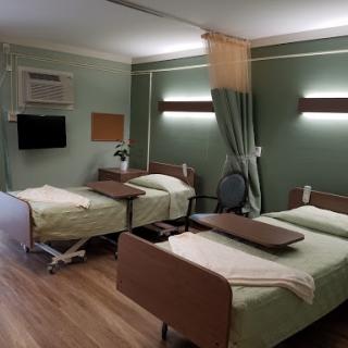An interior view of a hospital room featuring two beds and medical furnishings.
