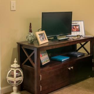 A wooden entertainment unit with a television, framed photo, decorative items, and books.