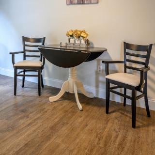 A cozy dining area with two chairs and a small round table on a wooden floor.