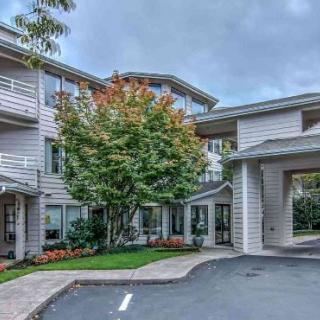 A residential building with a landscaped entrance and a cloudy sky overhead.