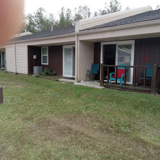 A view of two residential units with outdoor seating on a grassy area.