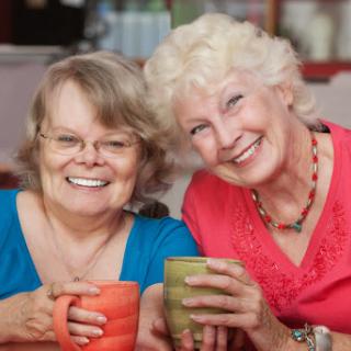 Two joyful friends enjoying a cozy moment over coffee.
