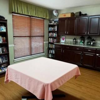 A home interior with a table, bookshelves, and cabinets near a window.