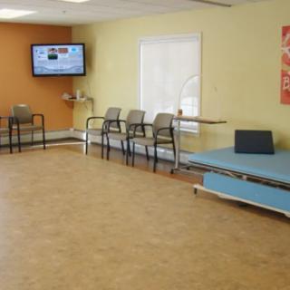 An empty waiting room with chairs, a TV, and light-colored walls.