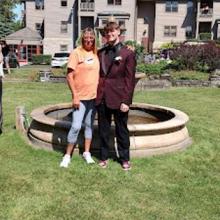 Two friends posing together by a decorative fountain in a garden.