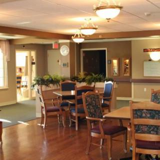 A cozy dining room with multiple tables and chairs, featuring warm lighting and wood flooring.