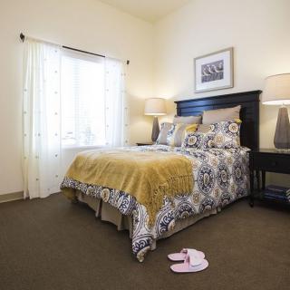 A cozy bedroom with a neatly made bed, bedside lamps, and decorative elements.