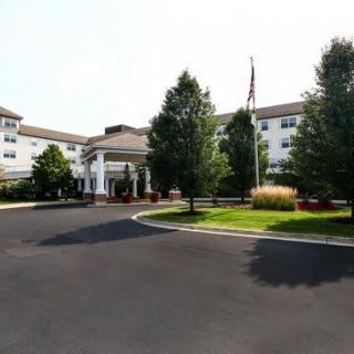 A large hotel building with trees and a driveway at the entrance.