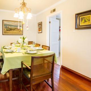A cozy dining room with a neatly set table ready for a meal, featuring wooden chairs and elegant artwork on the walls.