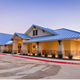 A modern building with a blue metal roof and well-maintained surroundings.