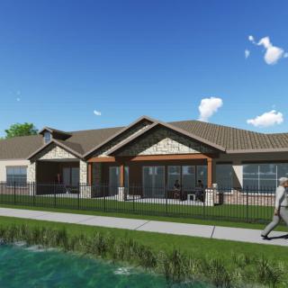 A modern residential house with a landscaped pathway by a pond under a blue sky.