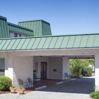 A building entrance with a green metal roof and outdoor seating.