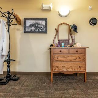 A cozy room with a vintage dresser and mirror, accompanied by a coat rack and wall decor.