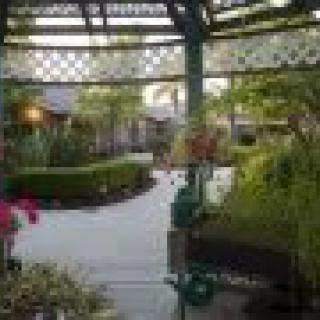 A serene garden view featuring a gazebo, lush greenery, and blooming flowers.