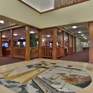 A spacious hotel lobby featuring a detailed floor mural and wooden accents.