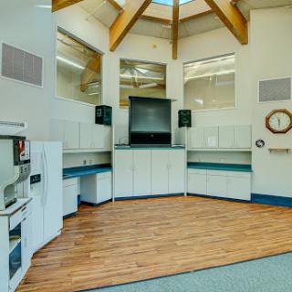 A modern interior space featuring wooden beams, a kitchenette area, and an open layout.