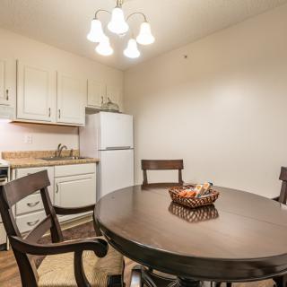 A cozy kitchen and dining area with a round wooden table, chairs, and a refrigerator.