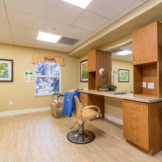 A well-lit salon interior with a styling chair, mirror, and wooden cabinets.