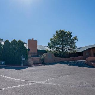 A sunny view of a building with a parking lot and trees.