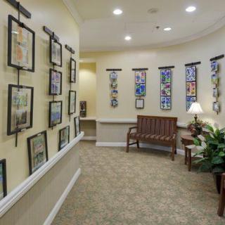 A hallway designed as an art gallery with framed pictures on the walls, a bench for seating, and decorative plants.