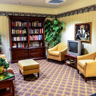 A cozy living room with bookshelves, armchairs, and a television.