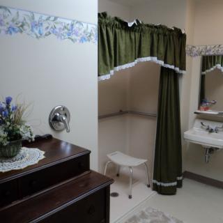 A bathroom with a shower area featuring a green curtain, a sink, and floral decorations.