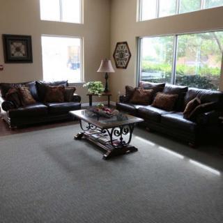 A spacious living room with large windows, featuring two sofas and a decorative coffee table.