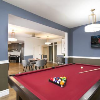 A modern game room featuring a red pool table and stylish furnishings.