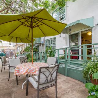 A cozy outdoor patio area with tables and umbrellas, surrounded by greenery.