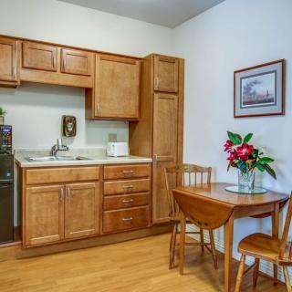 A cozy kitchen area with wooden cabinets, a small dining table, and a vase of flowers.