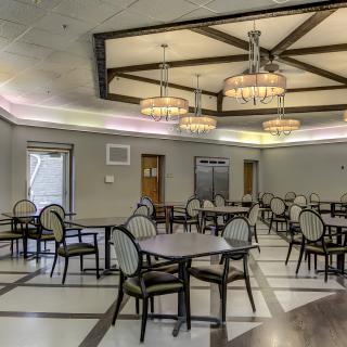 A spacious dining area with elegant chandeliers, round tables, and upholstered chairs.