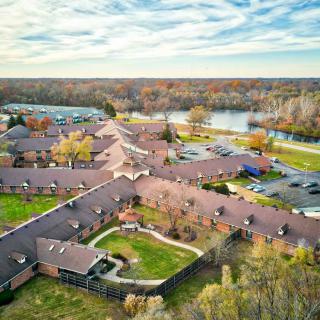 Aerial view of a large building complex surrounded by autumn foliage near a river.